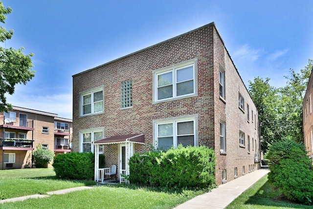 multi unit property featuring brick siding and a front yard