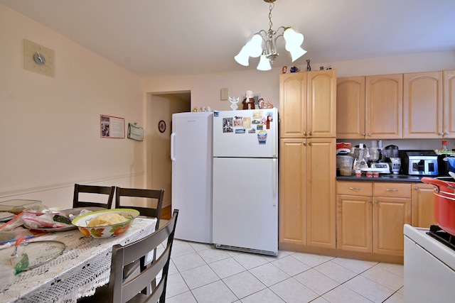 kitchen featuring freestanding refrigerator, light brown cabinetry, a chandelier, light tile patterned floors, and pendant lighting