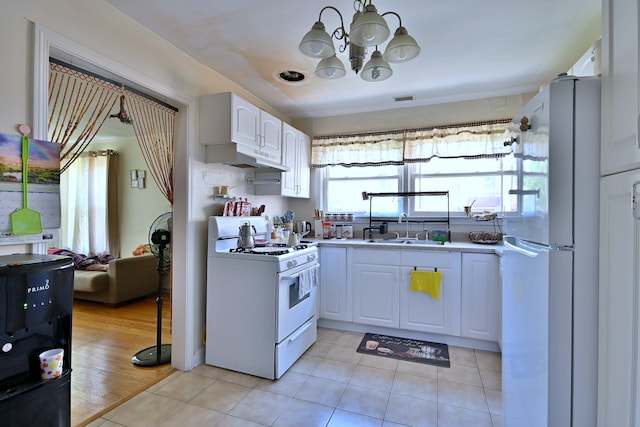 kitchen featuring white appliances, white cabinets, a chandelier, light countertops, and under cabinet range hood