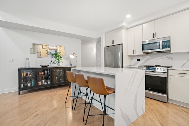 1225 N Paulina St Unit 3S, Chicago, IL 60622 - kitchen featuring appliances with stainless steel finishes, a kitchen island, light wood-type flooring, a kitchen breakfast bar, and recessed lighting