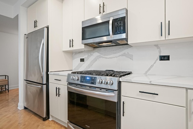 1225 N Paulina St Unit 3S, Chicago, IL 60622 - kitchen with stainless steel appliances, light wood-style floors, white cabinets, decorative backsplash, and light stone counters