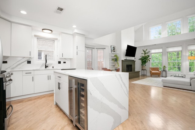 1225 N Paulina St Unit 3S, Chicago, IL 60622 - kitchen featuring wine cooler, a fireplace with raised hearth, open floor plan, healthy amount of natural light, and a high ceiling