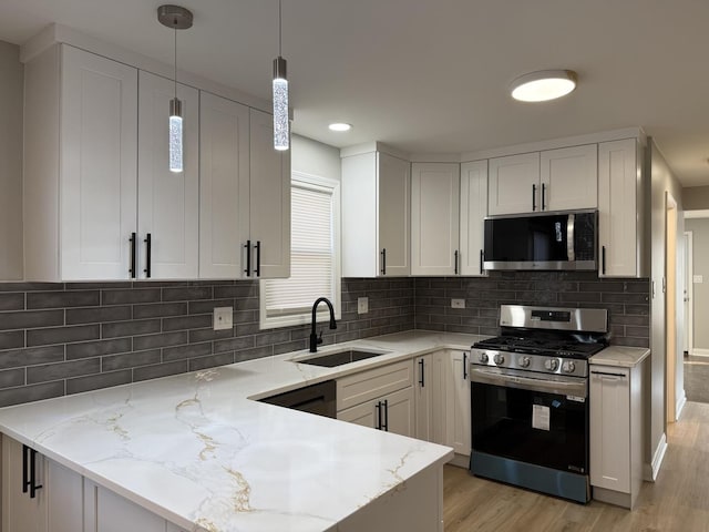 2620 W 36th Pl, Chicago, IL 60632 - kitchen featuring appliances with stainless steel finishes, light stone counters, light wood-style floors, a peninsula, and white cabinets