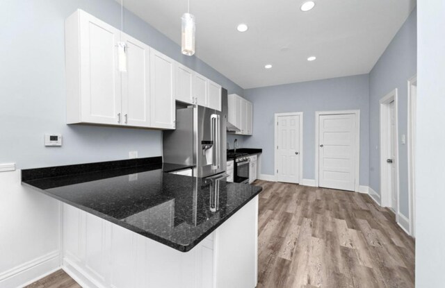 4329 S Wood St, Chicago, IL 60609 - kitchen featuring stainless steel appliances, wood finished floors, a peninsula, dark stone countertops, and white cabinets