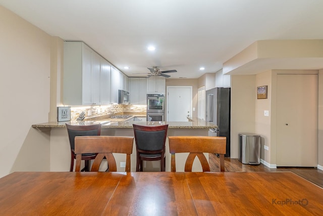 1812 S State St Unit 28, Chicago, IL 60616 - kitchen with appliances with stainless steel finishes, a peninsula, light stone countertops, recessed lighting, and tasteful backsplash