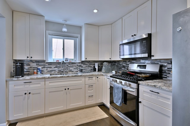 6869 N Overhill Ave Unit 2B, Chicago, IL 60631 - kitchen with stainless steel appliances, white cabinets, tasteful backsplash, light stone countertops, and wood finished floors