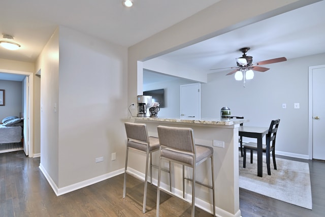 6869 N Overhill Ave Unit 2B, Chicago, IL 60631 - kitchen with dark wood-style floors, a breakfast bar area, ceiling fan, and light stone counters