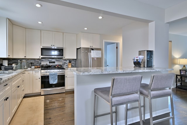 6869 N Overhill Ave Unit 2B, Chicago, IL 60631 - kitchen featuring appliances with stainless steel finishes, white cabinetry, decorative backsplash, a breakfast bar, and recessed lighting