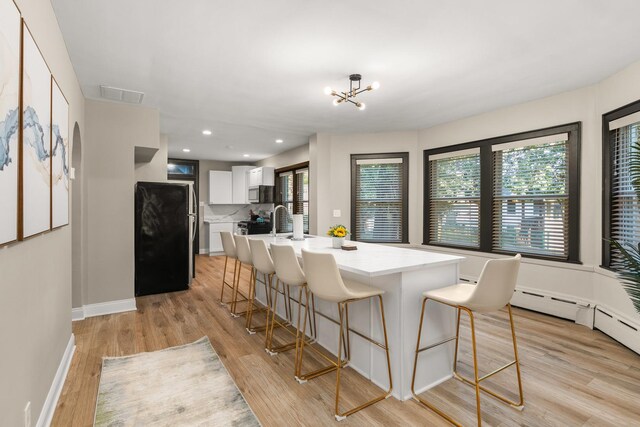 5901 N Navarre Ave, Chicago, IL 60631 - kitchen featuring appliances with stainless steel finishes, a breakfast bar, light wood-style flooring, white cabinetry, and light countertops