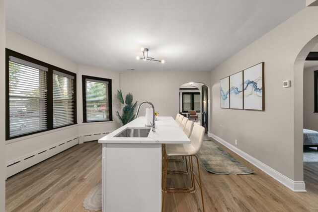 5901 N Navarre Ave, Chicago, IL 60631 - dining space with arched walkways, light wood-style flooring, a baseboard heating unit, and a chandelier