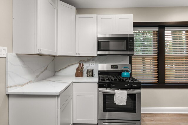 5901 N Navarre Ave, Chicago, IL 60631 - kitchen with stainless steel appliances, white cabinetry, light wood finished floors, light stone counters, and decorative backsplash