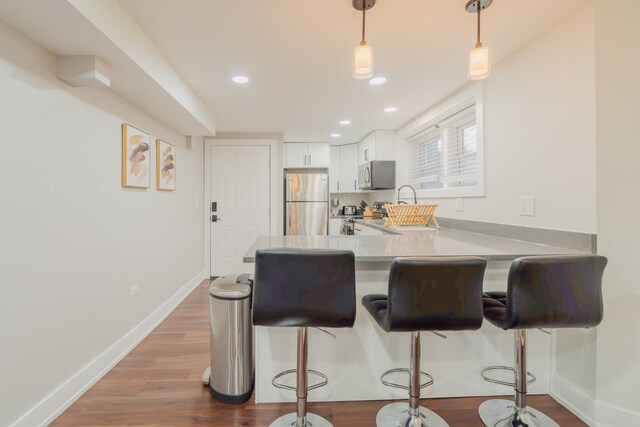 5901 N Navarre Ave, Chicago, IL 60631 - kitchen featuring stainless steel appliances, a kitchen bar, a peninsula, white cabinetry, and pendant lighting