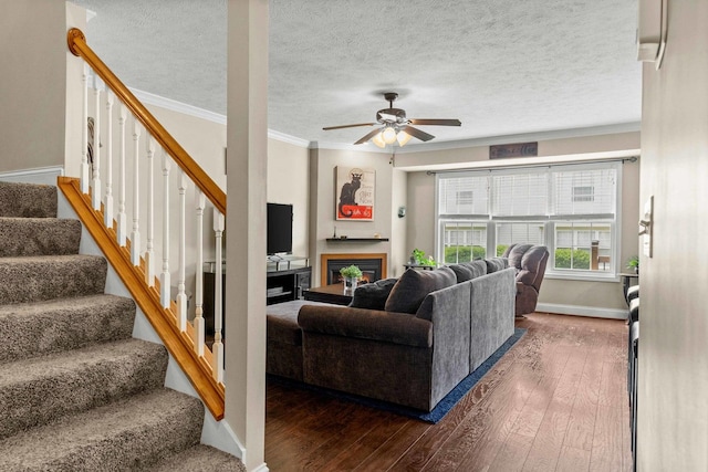 1201 Riviera Dr, Bloomington, IL 61701 - living room with crown molding, ceiling fan, hardwood / wood-style flooring, a warm lit fireplace, and stairs