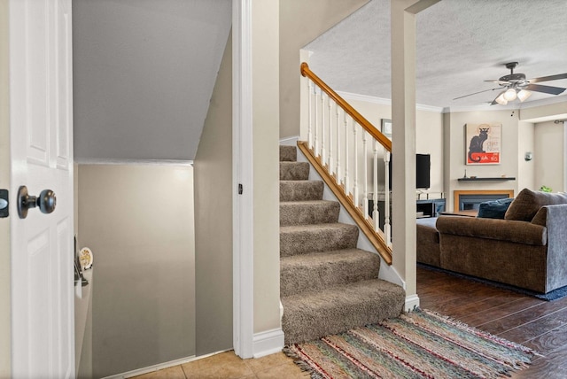 1201 Riviera Dr, Bloomington, IL 61701 - stairs with a ceiling fan, a glass covered fireplace, crown molding, and a textured ceiling