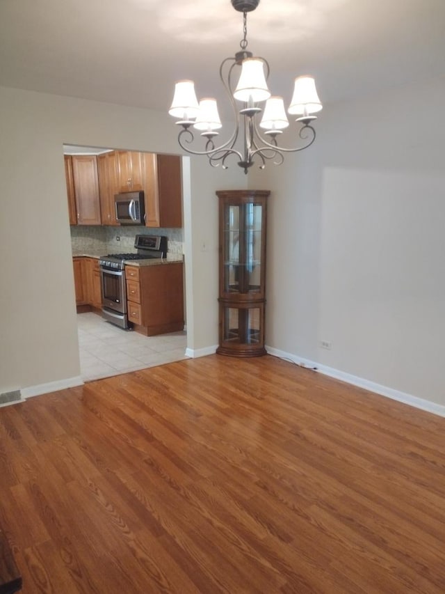 1544 Towhee Ln, Naperville, IL 60565 - kitchen with stainless steel appliances, a chandelier, brown cabinetry, light wood-style floors, and backsplash
