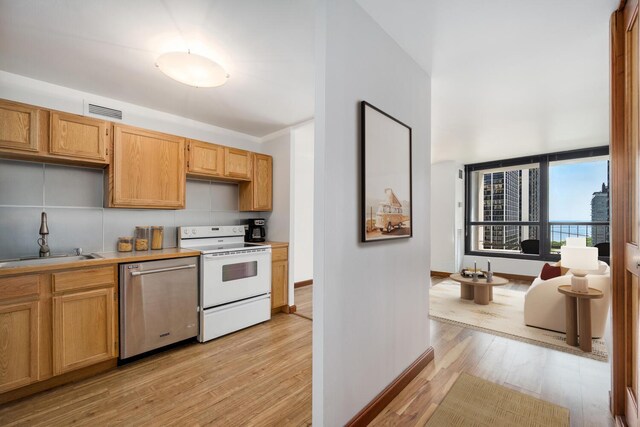 1030 N State St Unit 9G, Chicago, IL 60610 - kitchen featuring white electric stove, dishwasher, light wood-style floors, and light countertops