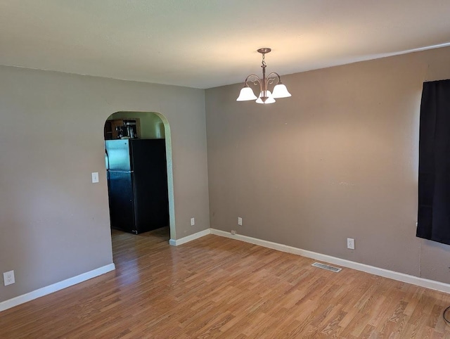 707 E Van Allen St, Tuscola, IL 61953 - spare room with arched walkways, light wood-type flooring, and a chandelier
