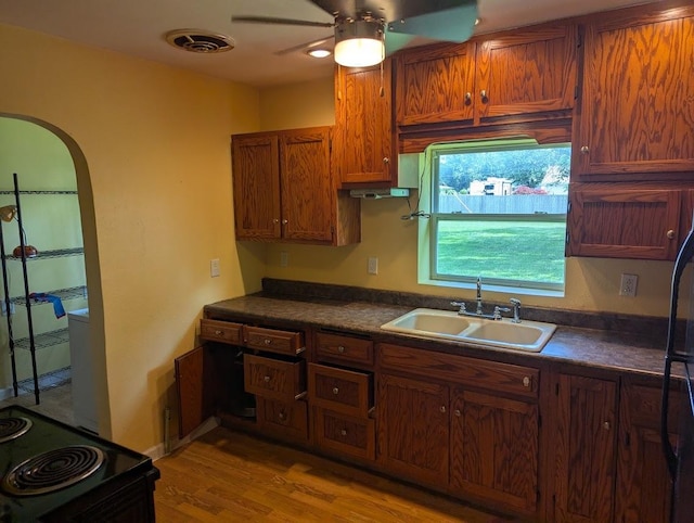 707 E Van Allen St, Tuscola, IL 61953 - kitchen featuring dark countertops, a ceiling fan, electric range, arched walkways, and brown cabinetry