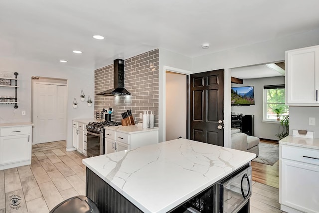 235 Fox Trail Ct, Bourbonnais, IL 60914 - kitchen featuring wall chimney exhaust hood, stainless steel gas range, white cabinetry, light stone countertops, and black microwave