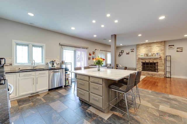 202 Dallas Dr, Bartlett, IL 60103 - kitchen featuring stainless steel dishwasher, recessed lighting, stone tile flooring, a brick fireplace, and a kitchen breakfast bar