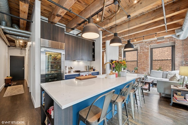 106 N Aberdeen St Unit 3A, Chicago, IL 60607 - kitchen with brick wall, a wooden ceiling with exposed beams, dark wood-type flooring, light countertops, and a breakfast bar area
