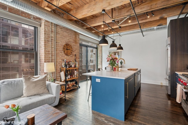 106 N Aberdeen St Unit 3A, Chicago, IL 60607 - kitchen with a wooden ceiling with exposed beams, dark wood-type flooring, a center island with sink, brick wall, and a breakfast bar