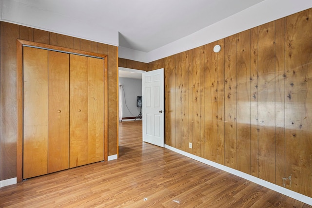 906 N State St, Marengo, IL 60152 - unfurnished bedroom featuring wooden walls, light wood finished floors, and a closet