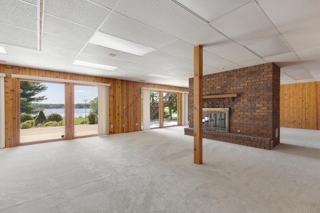 39081 N Sheridan Rd, Antioch, IL 60002 - unfurnished living room with wooden walls, carpet flooring, a paneled ceiling, a brick fireplace, and a water view