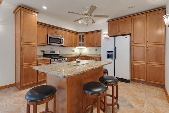 39081 N Sheridan Rd, Antioch, IL 60002 - kitchen with stainless steel appliances, brown cabinetry, a kitchen bar, recessed lighting, and glass insert cabinets