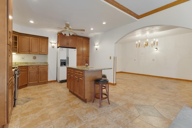 39081 N Sheridan Rd, Antioch, IL 60002 - kitchen with white refrigerator with ice dispenser, arched walkways, a ceiling fan, brown cabinetry, and a kitchen island