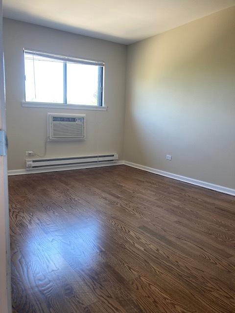 442 E Osage Ln Unit 3A, Palatine, IL 60067 - spare room featuring a baseboard radiator, a wall unit AC, and dark wood finished floors