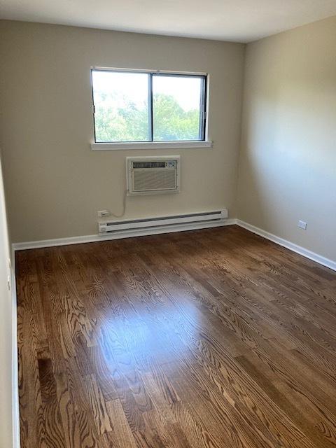 442 E Osage Ln Unit 3A, Palatine, IL 60067 - spare room with a wall mounted AC, a baseboard radiator, and wood finished floors