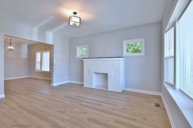 8004 S Ada St, Chicago, IL 60620 - unfurnished living room featuring light wood-style flooring, a brick fireplace, and a chandelier