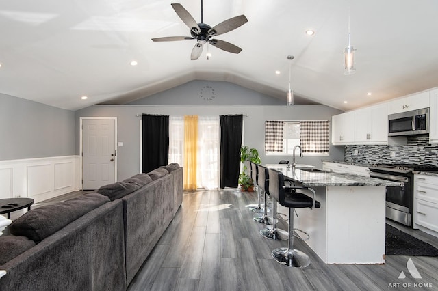 16956 Sunset Ridge Dr, Country Club Hills, IL 60478 - kitchen with appliances with stainless steel finishes, vaulted ceiling, dark wood finished floors, open floor plan, and a kitchen bar