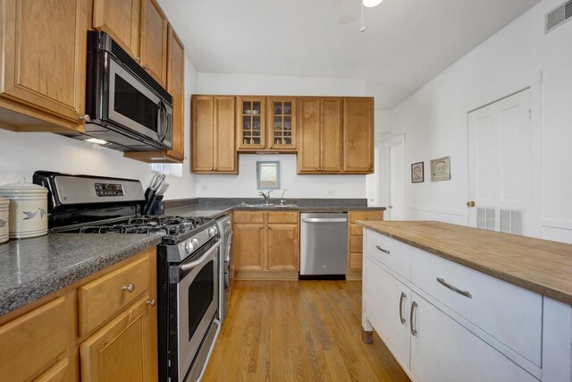 1848 W Cermak Rd Unit 3, Chicago, IL 60608 - kitchen with appliances with stainless steel finishes, wood finished floors, glass insert cabinets, and brown cabinetry