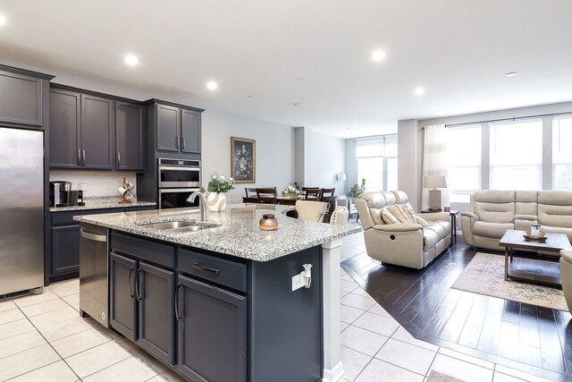 169 Waverly Ct, Bloomingdale, IL 60108 - kitchen with stainless steel appliances, light tile patterned floors, a kitchen island with sink, open floor plan, and recessed lighting