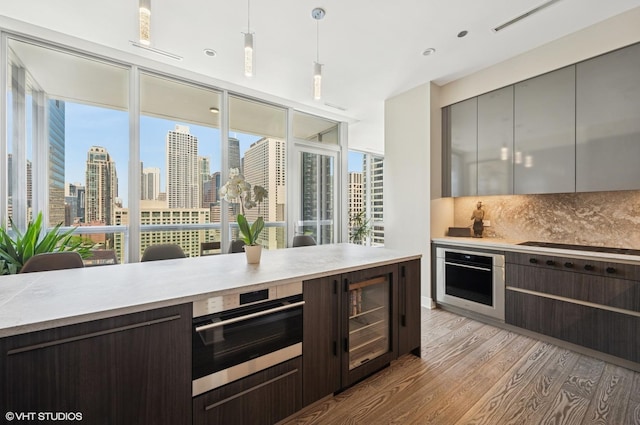 403 N Wabash Ave Unit 17C, Chicago, IL 60611 - kitchen with stainless steel oven, light wood-style flooring, modern cabinets, backsplash, and light countertops