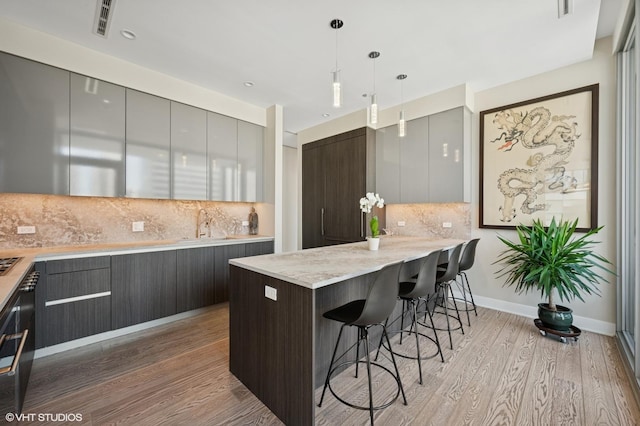 403 N Wabash Ave Unit 17C, Chicago, IL 60611 - kitchen with modern cabinets, a breakfast bar, light wood finished floors, hanging light fixtures, and gray cabinetry