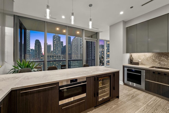 403 N Wabash Ave Unit 17C, Chicago, IL 60611 - kitchen featuring stainless steel oven, light wood-style floors, modern cabinets, light countertops, and backsplash