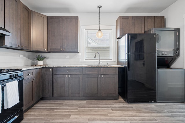 5043 W Argyle St, Chicago, IL 60630 - kitchen featuring black appliances, stacked washing machine and dryer, decorative backsplash, light stone counters, and dark brown cabinetry