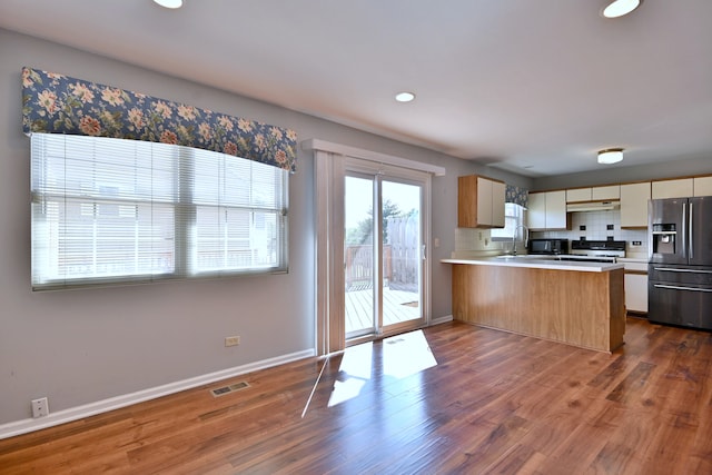 633 Ascot Ln, Streamwood, IL 60107 - kitchen with stainless steel fridge, a peninsula, under cabinet range hood, light countertops, and dark wood-type flooring