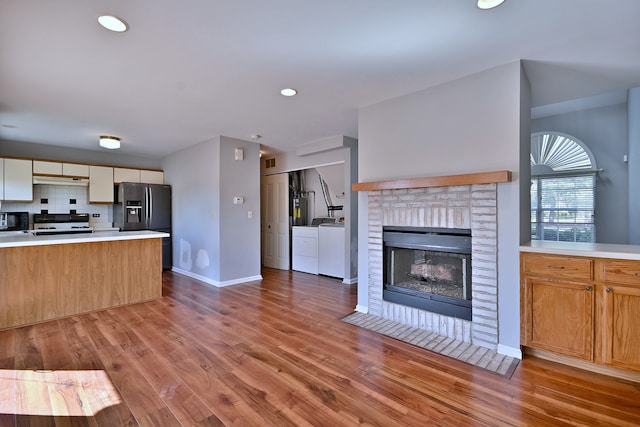 633 Ascot Ln, Streamwood, IL 60107 - kitchen featuring washing machine and clothes dryer, refrigerator with ice dispenser, range, a fireplace, and light countertops