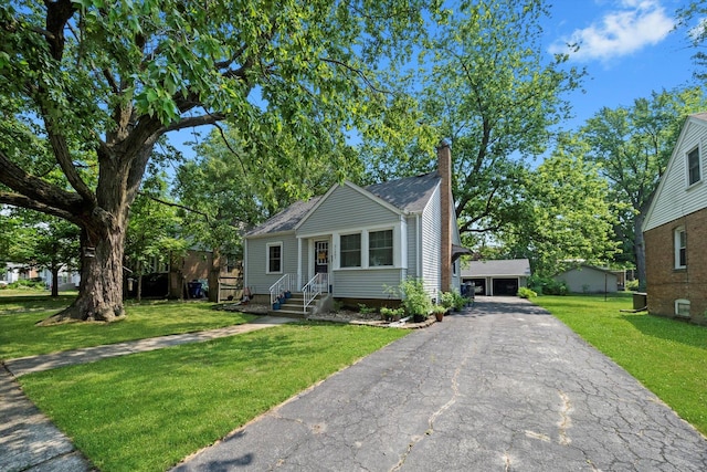 21207 Locust St, Matteson, IL 60443 - bungalow-style house featuring a chimney, a front lawn, asphalt driveway, an outbuilding, and roof with shingles