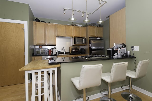 1621 S Halsted St Unit 405, Chicago, IL 60608 - kitchen featuring appliances with stainless steel finishes, dark countertops, a kitchen bar, and a peninsula