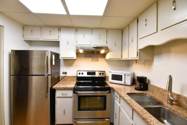 3856 S Parkway Dr Unit 1E, Northbrook, IL 60062 - kitchen featuring appliances with stainless steel finishes, under cabinet range hood, a drop ceiling, light stone counters, and white cabinetry