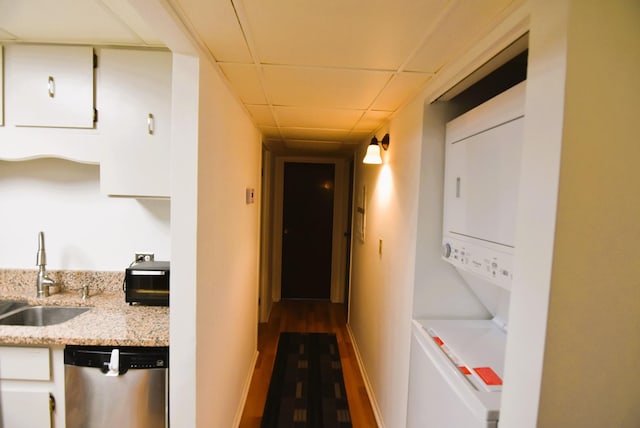 3856 S Parkway Dr Unit 1E, Northbrook, IL 60062 - kitchen with stainless steel dishwasher, stacked washing machine and dryer, white cabinetry, a drop ceiling, and light stone counters