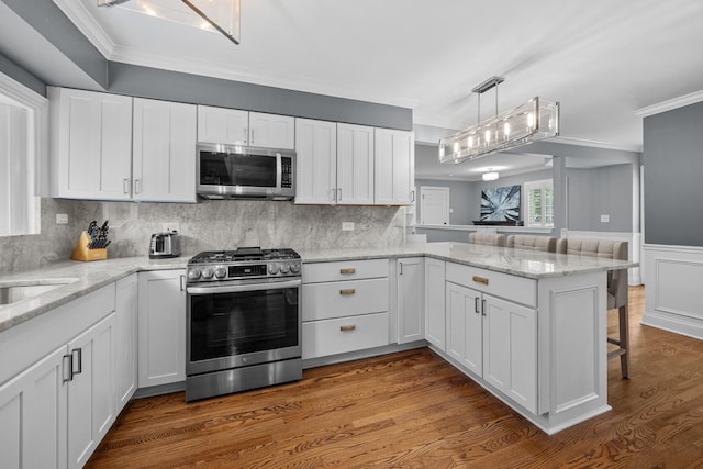 3 Old Valley Rd, Rolling Meadows, IL 60008 - kitchen with stainless steel appliances, a peninsula, ornamental molding, white cabinetry, and a kitchen breakfast bar