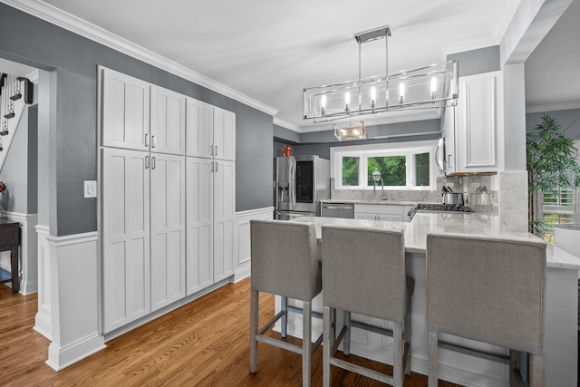 3 Old Valley Rd, Rolling Meadows, IL 60008 - kitchen featuring stainless steel appliances, a peninsula, white cabinetry, crown molding, and a kitchen bar