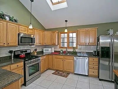 9417 W Steger Rd, Frankfort, IL 60423 - kitchen featuring appliances with stainless steel finishes, lofted ceiling, hanging light fixtures, a skylight, and light tile patterned floors
