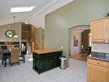 9417 W Steger Rd, Frankfort, IL 60423 - kitchen with light brown cabinets, light tile patterned floors, arched walkways, vaulted ceiling, and a skylight